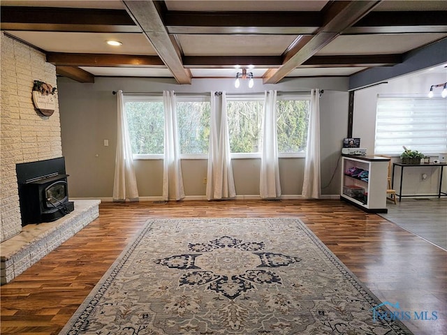 unfurnished living room featuring a healthy amount of sunlight, wood-type flooring, and coffered ceiling