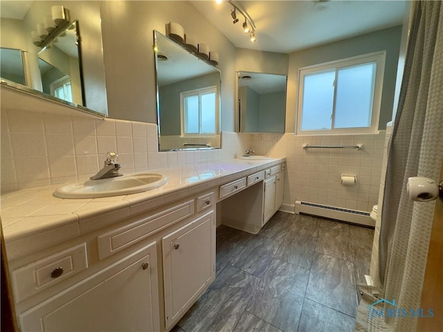 bathroom with a baseboard radiator, tile walls, and vanity