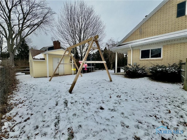 yard covered in snow featuring a shed and a playground