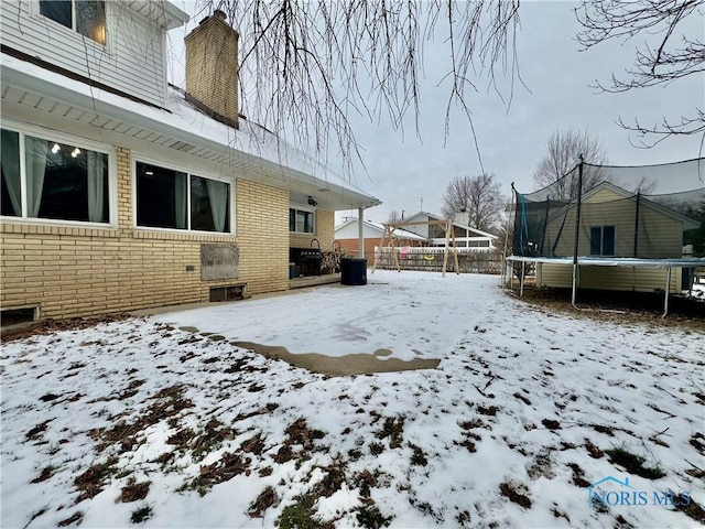 yard layered in snow with a trampoline