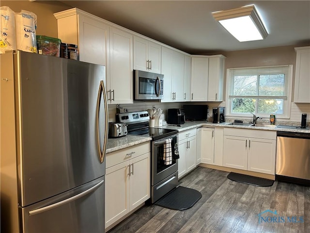 kitchen with light stone counters, sink, white cabinets, and appliances with stainless steel finishes