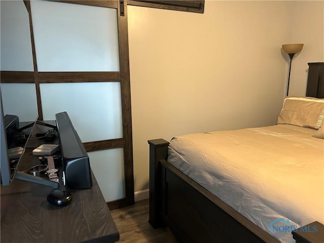 bedroom featuring dark wood-type flooring and a barn door