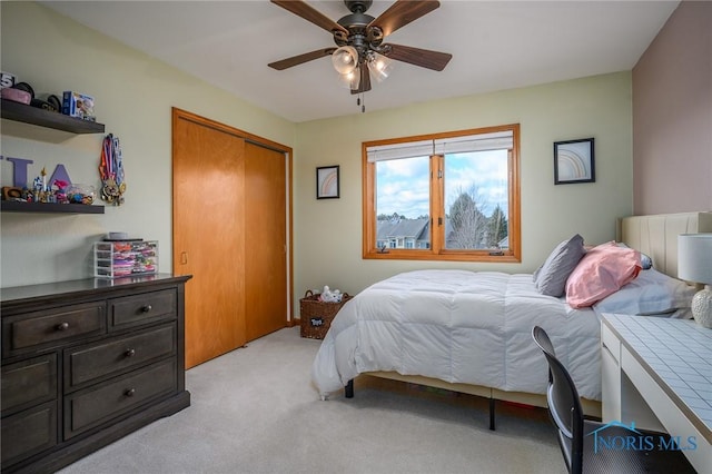 carpeted bedroom with ceiling fan and a closet