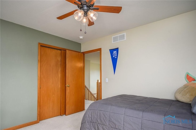 bedroom with ceiling fan, light colored carpet, and a closet