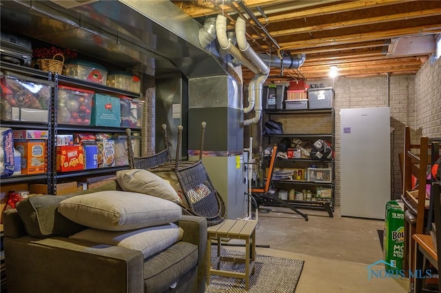 basement featuring white refrigerator and brick wall