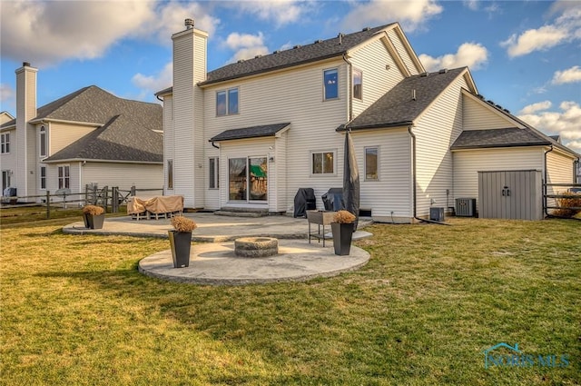 rear view of property with a patio, a lawn, cooling unit, and a fire pit