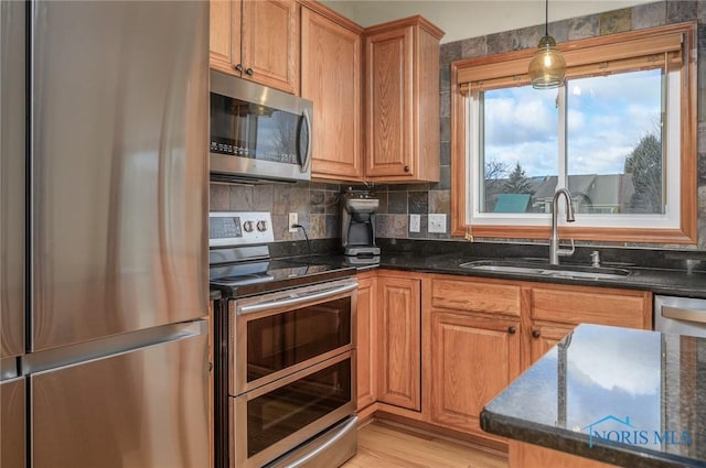 kitchen featuring tasteful backsplash, sink, dark stone countertops, hanging light fixtures, and stainless steel appliances