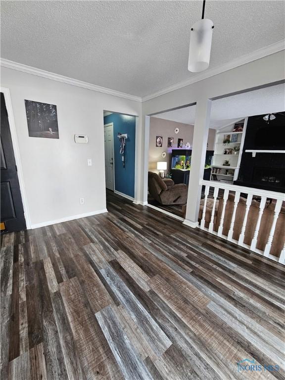 unfurnished living room with ornamental molding, dark hardwood / wood-style floors, and a textured ceiling