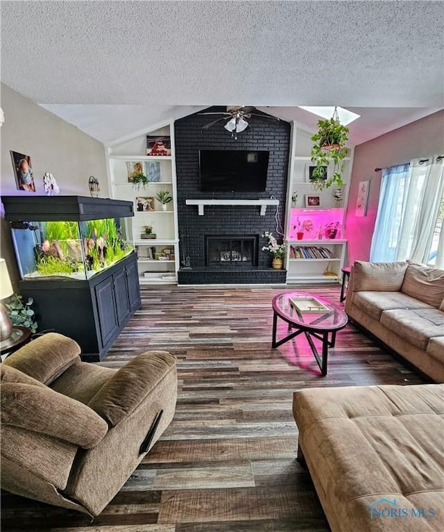 living room featuring lofted ceiling, dark wood-type flooring, built in features, a fireplace, and a textured ceiling