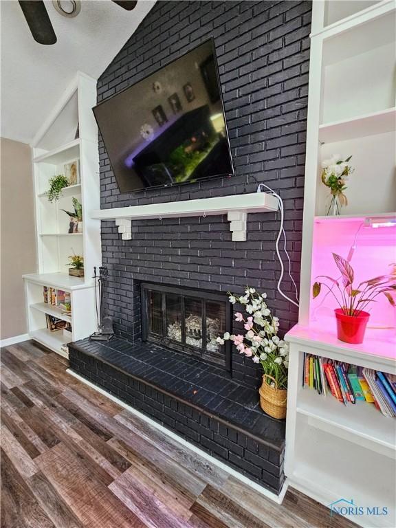 interior details featuring built in shelves, ceiling fan, wood-type flooring, and a fireplace