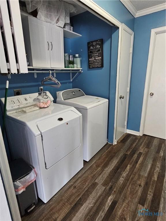 laundry room with crown molding, independent washer and dryer, dark wood-type flooring, and cabinets