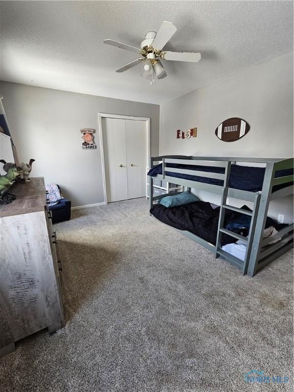 carpeted bedroom featuring ceiling fan, a textured ceiling, and a closet