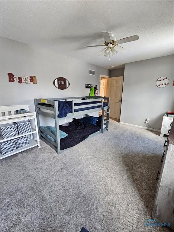 carpeted bedroom featuring ceiling fan and a textured ceiling