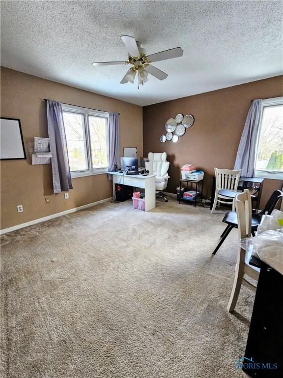 carpeted home office featuring ceiling fan and a textured ceiling