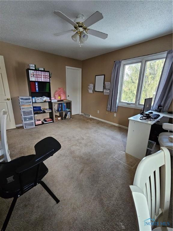 interior space featuring ceiling fan, carpet floors, and a textured ceiling