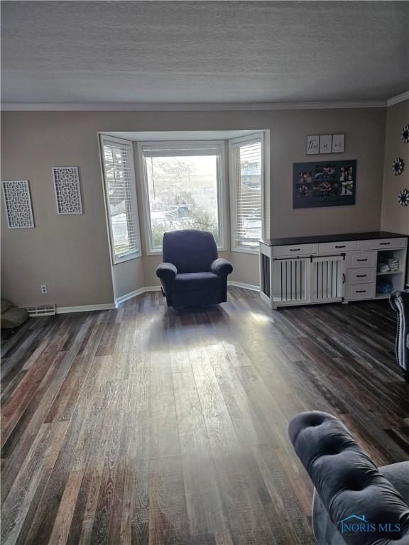 sitting room featuring hardwood / wood-style flooring, ornamental molding, and a textured ceiling