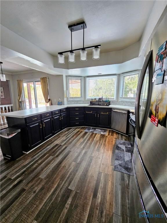 kitchen with hanging light fixtures, a healthy amount of sunlight, kitchen peninsula, and stainless steel appliances