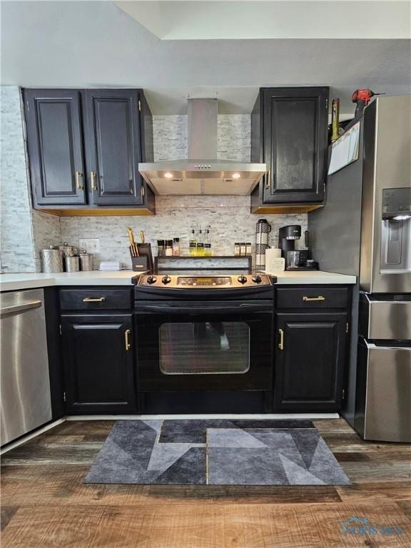 kitchen featuring appliances with stainless steel finishes, decorative backsplash, dark hardwood / wood-style flooring, and wall chimney exhaust hood