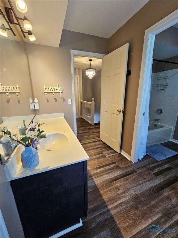 bathroom featuring vanity, hardwood / wood-style floors, a chandelier, and shower / bathing tub combination