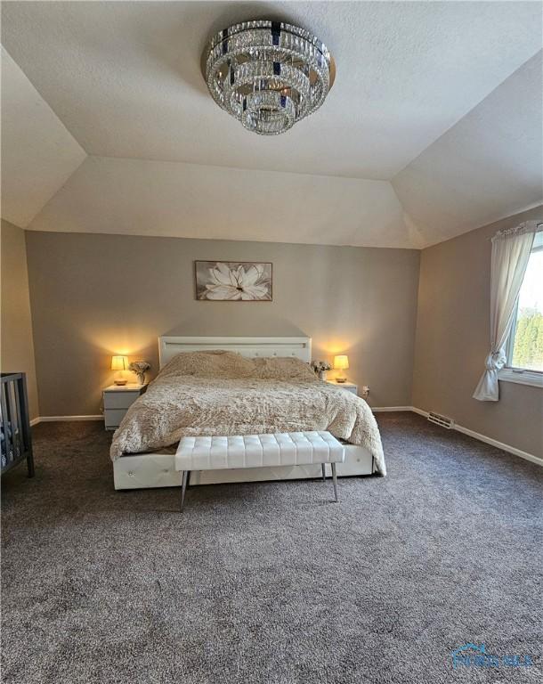 bedroom featuring lofted ceiling, a tray ceiling, dark carpet, and a textured ceiling