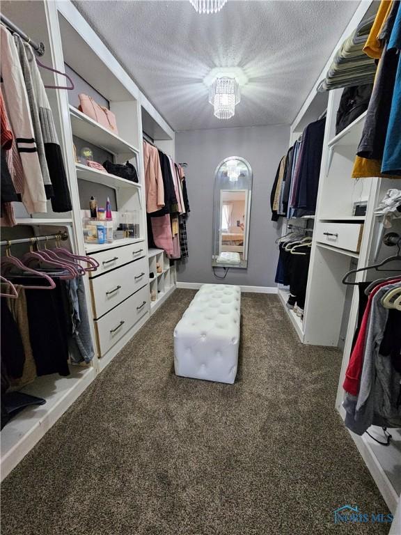 spacious closet featuring a notable chandelier and dark carpet