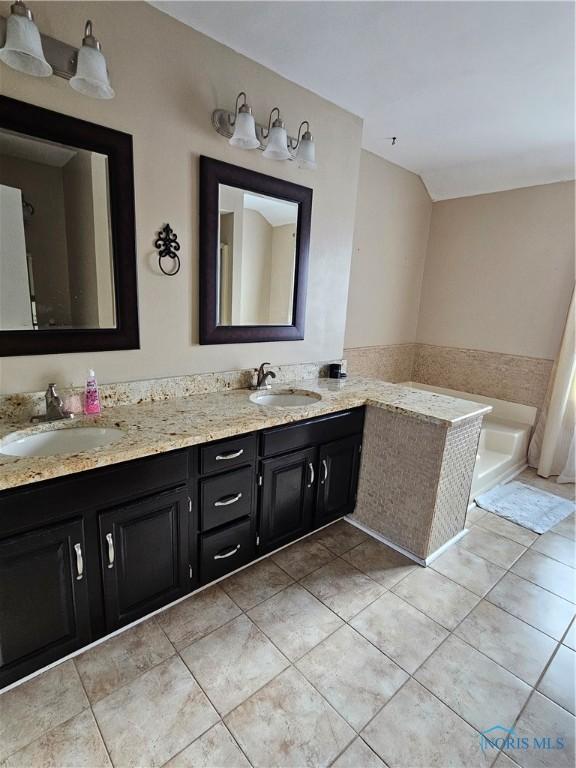 bathroom with vanity, tiled tub, and tile patterned floors