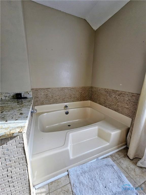 bathroom featuring a bathing tub and lofted ceiling