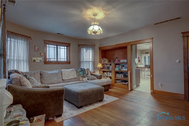 living area with baseboards, visible vents, and light wood-style flooring