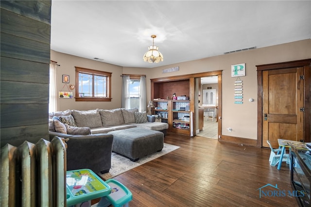 living room featuring dark wood-style flooring, visible vents, and baseboards