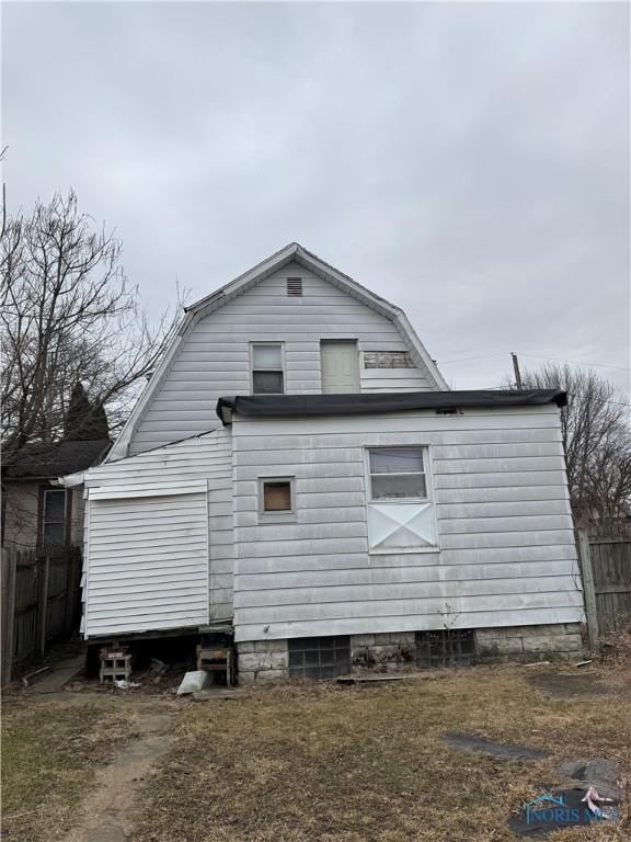 view of side of home featuring fence and a gambrel roof