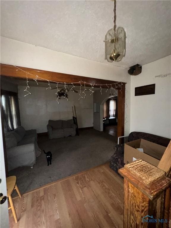 living area with arched walkways and wood finished floors