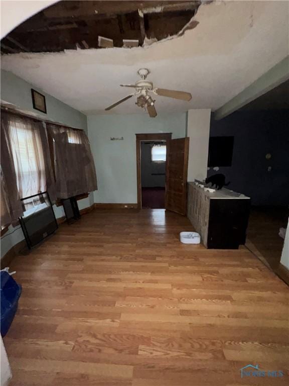 unfurnished living room featuring light wood-style floors, baseboards, and a ceiling fan