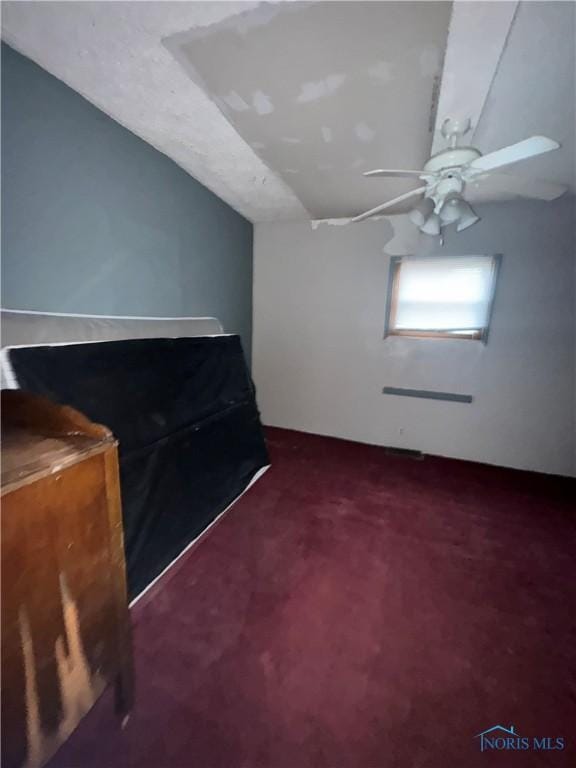 unfurnished bedroom featuring a ceiling fan, carpet, and lofted ceiling