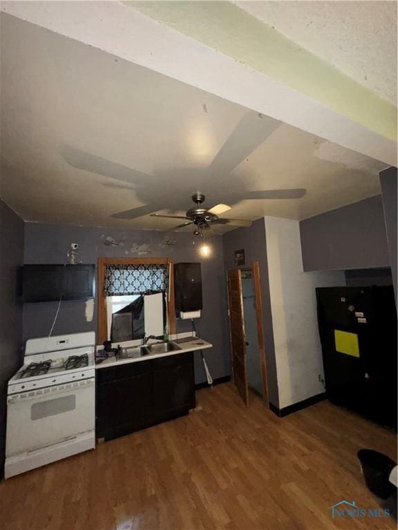 kitchen featuring white gas stove, light countertops, a ceiling fan, a sink, and wood finished floors