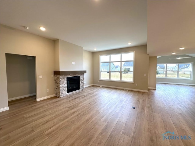 unfurnished living room featuring ceiling fan, a fireplace, and light hardwood / wood-style floors