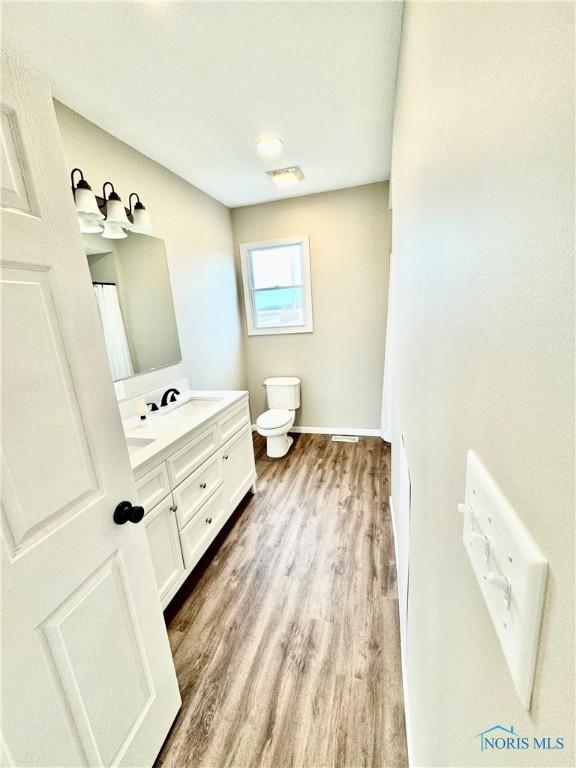 bathroom with wood-type flooring, vanity, and toilet