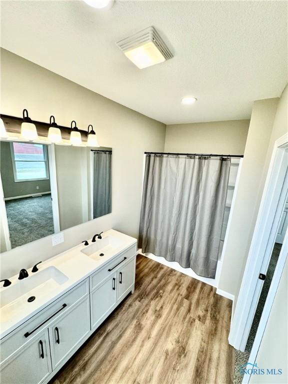 bathroom with hardwood / wood-style flooring, vanity, and a textured ceiling