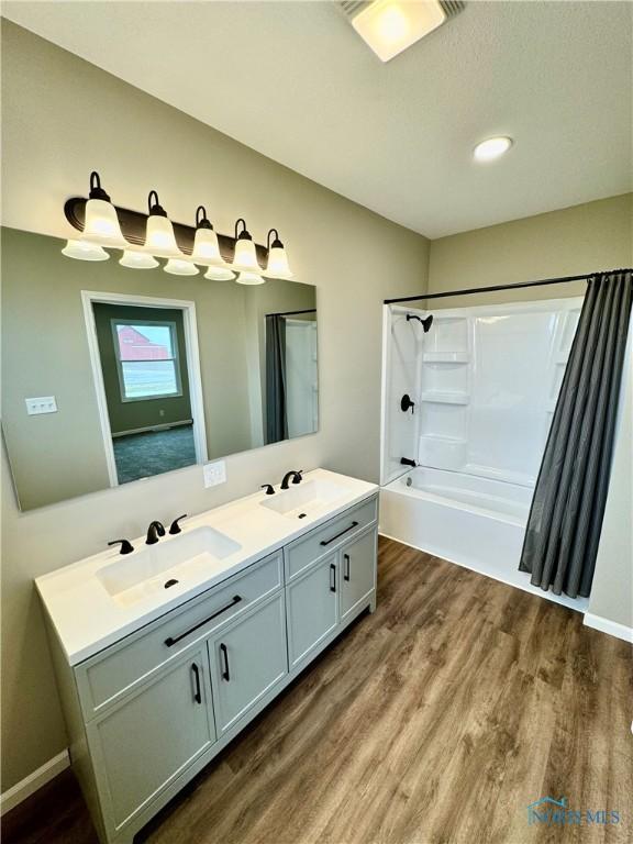 bathroom with hardwood / wood-style flooring, vanity, and shower / bath combination with curtain