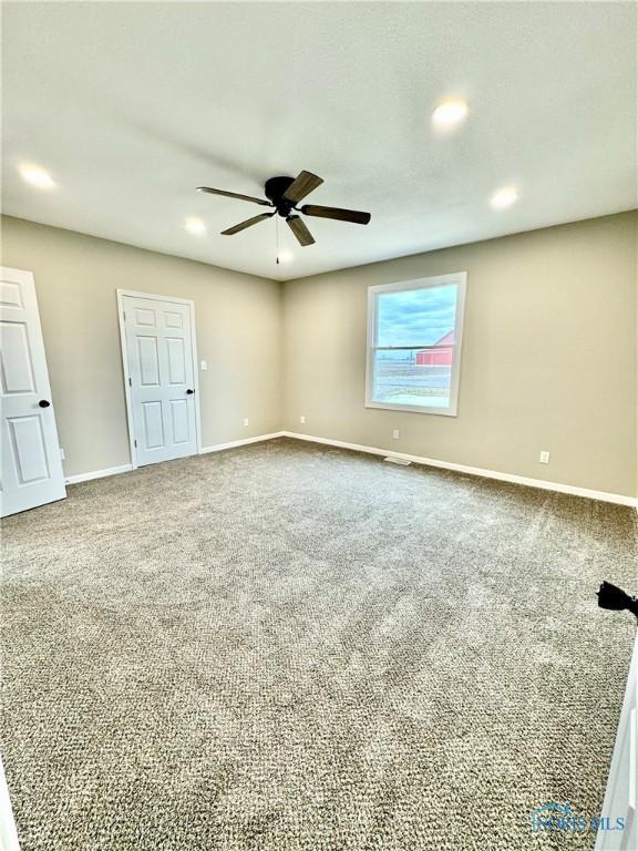 unfurnished room with ceiling fan and carpet