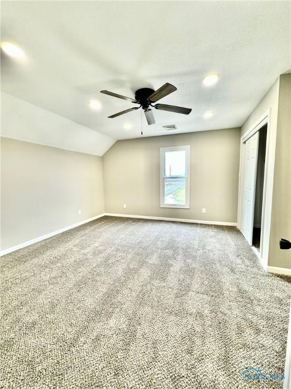 unfurnished room featuring vaulted ceiling, carpet, and ceiling fan