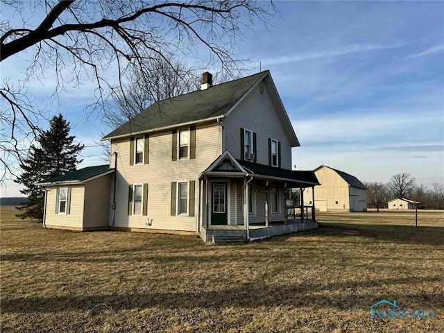 back of property featuring a yard and covered porch