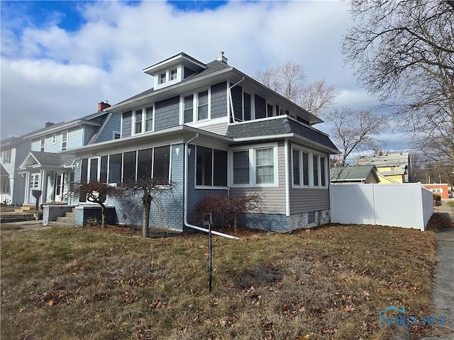 view of property exterior with a sunroom and a lawn