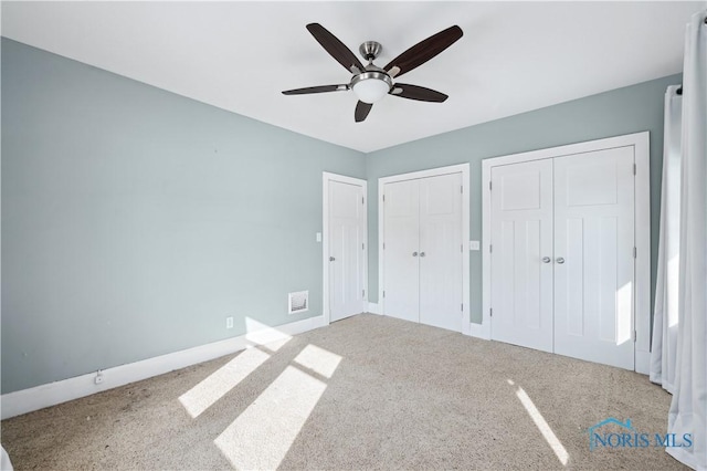 unfurnished bedroom with multiple closets, carpet, and ceiling fan