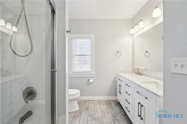 bathroom with vanity, toilet, hardwood / wood-style floors, and a shower