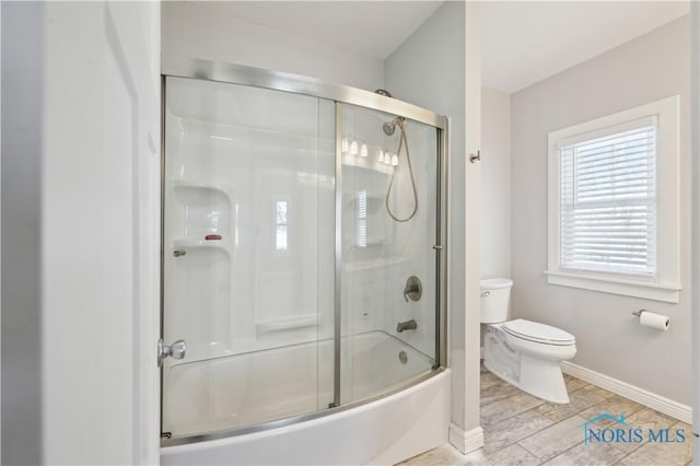 bathroom featuring bath / shower combo with glass door and toilet