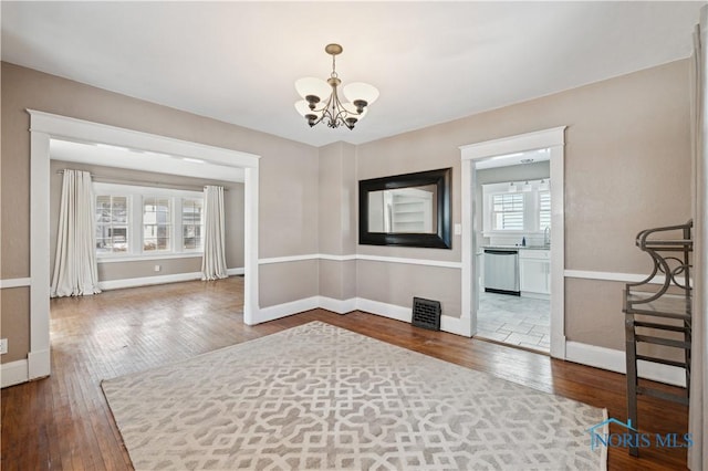 unfurnished dining area with hardwood / wood-style flooring, sink, and a notable chandelier