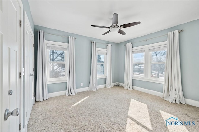 unfurnished bedroom with multiple windows, light carpet, and ceiling fan