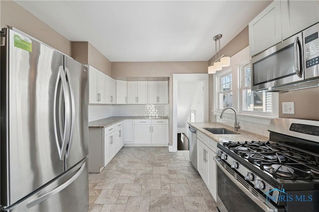 kitchen featuring white cabinetry, appliances with stainless steel finishes, sink, and light stone counters