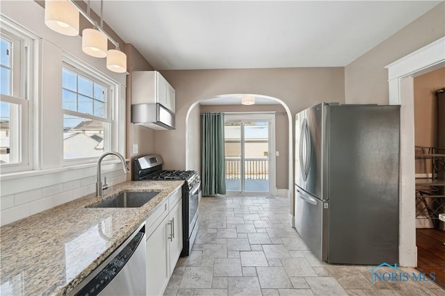 kitchen featuring pendant lighting, sink, appliances with stainless steel finishes, light stone counters, and white cabinets