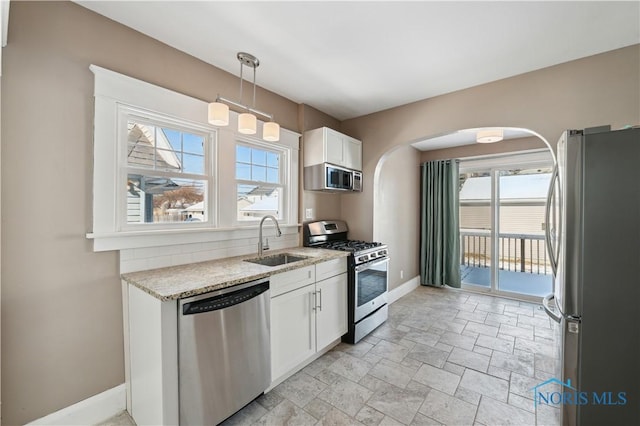 kitchen featuring sink, white cabinetry, decorative light fixtures, stainless steel appliances, and light stone countertops